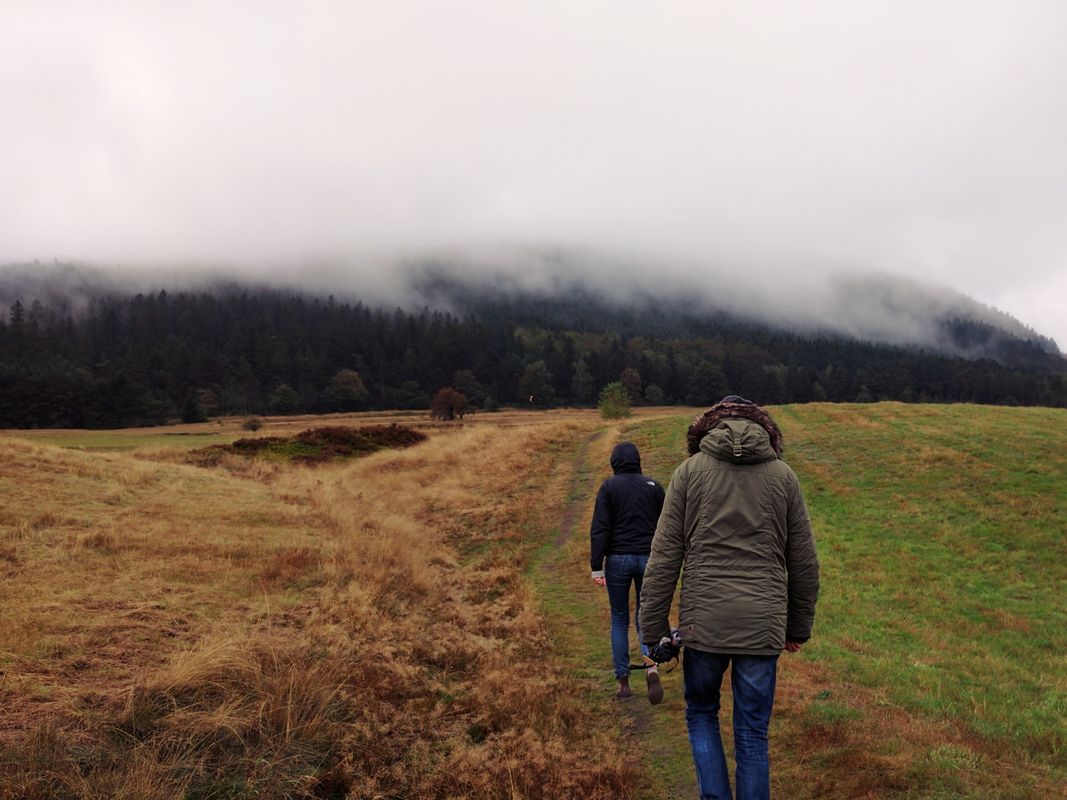 Two people walking a rural property through open countryside