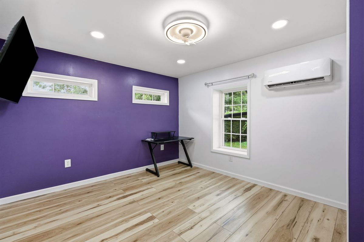 Addition bedroom with mini split, purple accent wall, desk, and clerestory windows