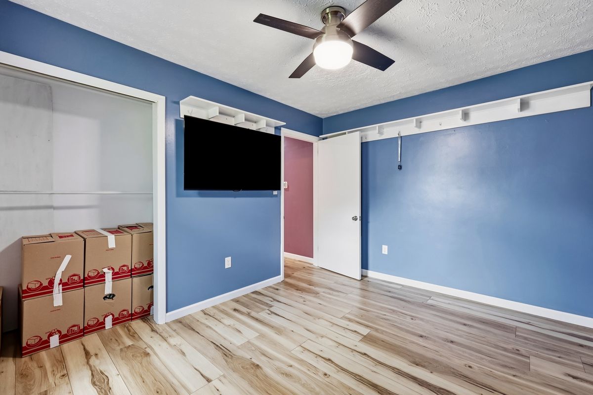 Bedroom with sliding mirror closet doors, wall-mounted TV, and ceiling fan