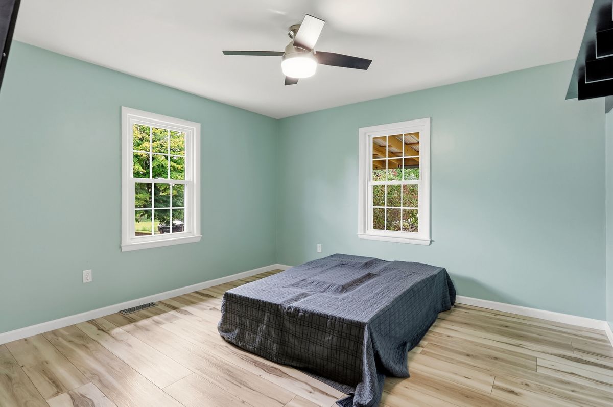 Bedroom with sage green walls, ceiling fan, and two windows