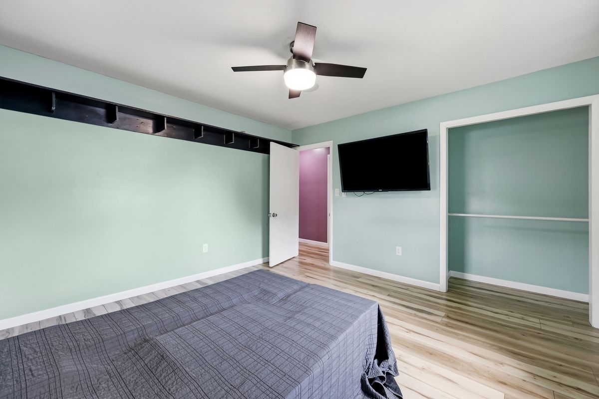 Bedroom with built-in shelf rail, wall-mounted TV, and closet
