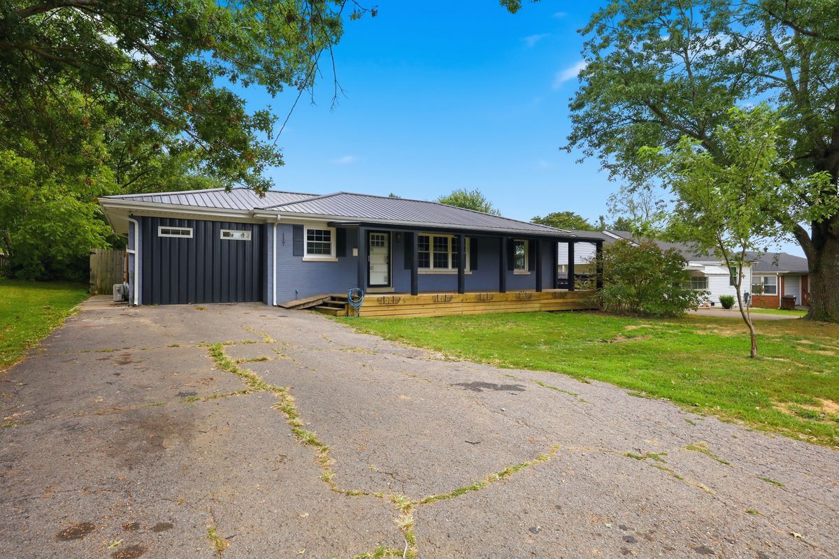 Front from driveway showing garage, metal roof, and covered porch
