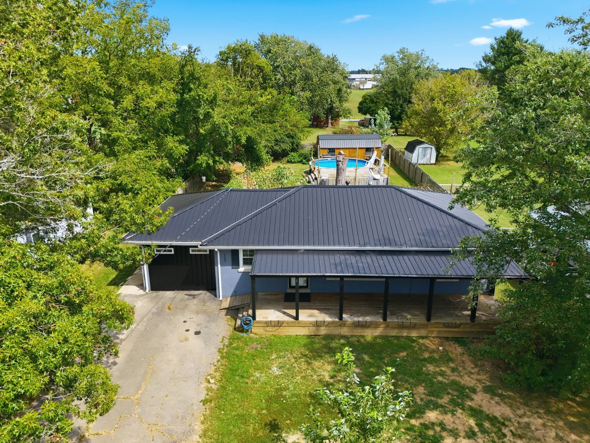 Aerial view of 117 Debbie Avenue showing metal roof, pool, deck, and backyard