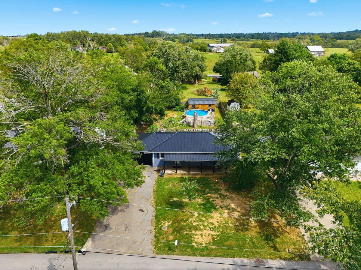 Aerial from street showing home, pool behind, and neighborhood