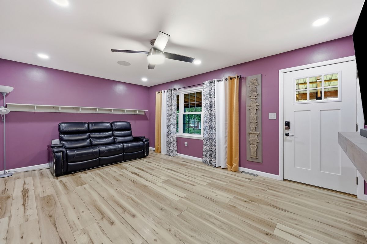 Living room with ceiling speaker, leather sofa, and keyless entry door to porch