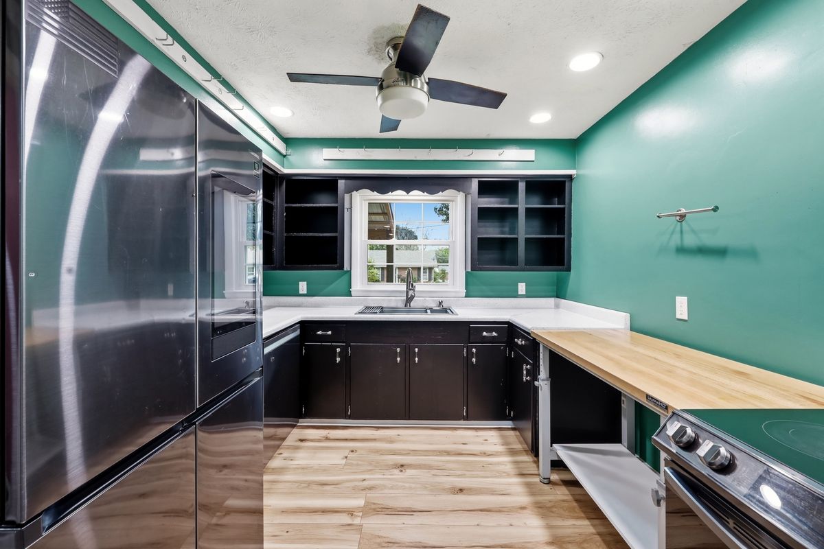 U-shaped kitchen with dark cabinets, white counters, and window over sink