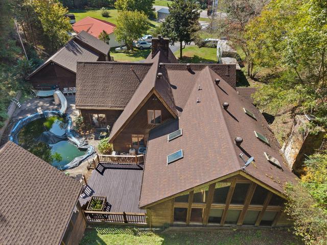 Aerial showing the home, garage, and tree-covered land