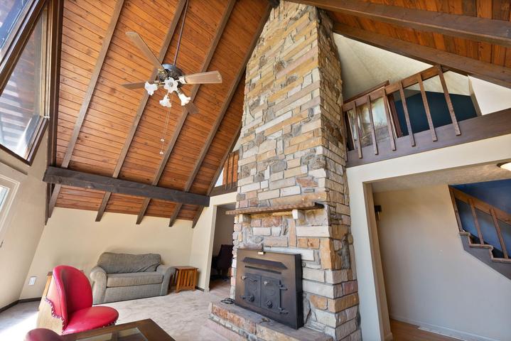 Great room with soaring cedar ceilings, two-story windows, and stone fireplace