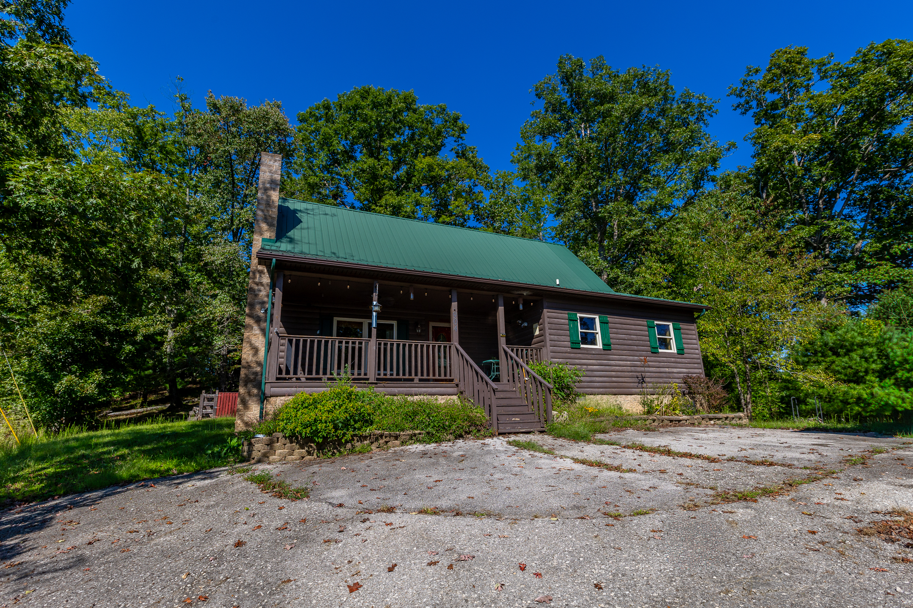Front of log home with covered porch and green metal roof