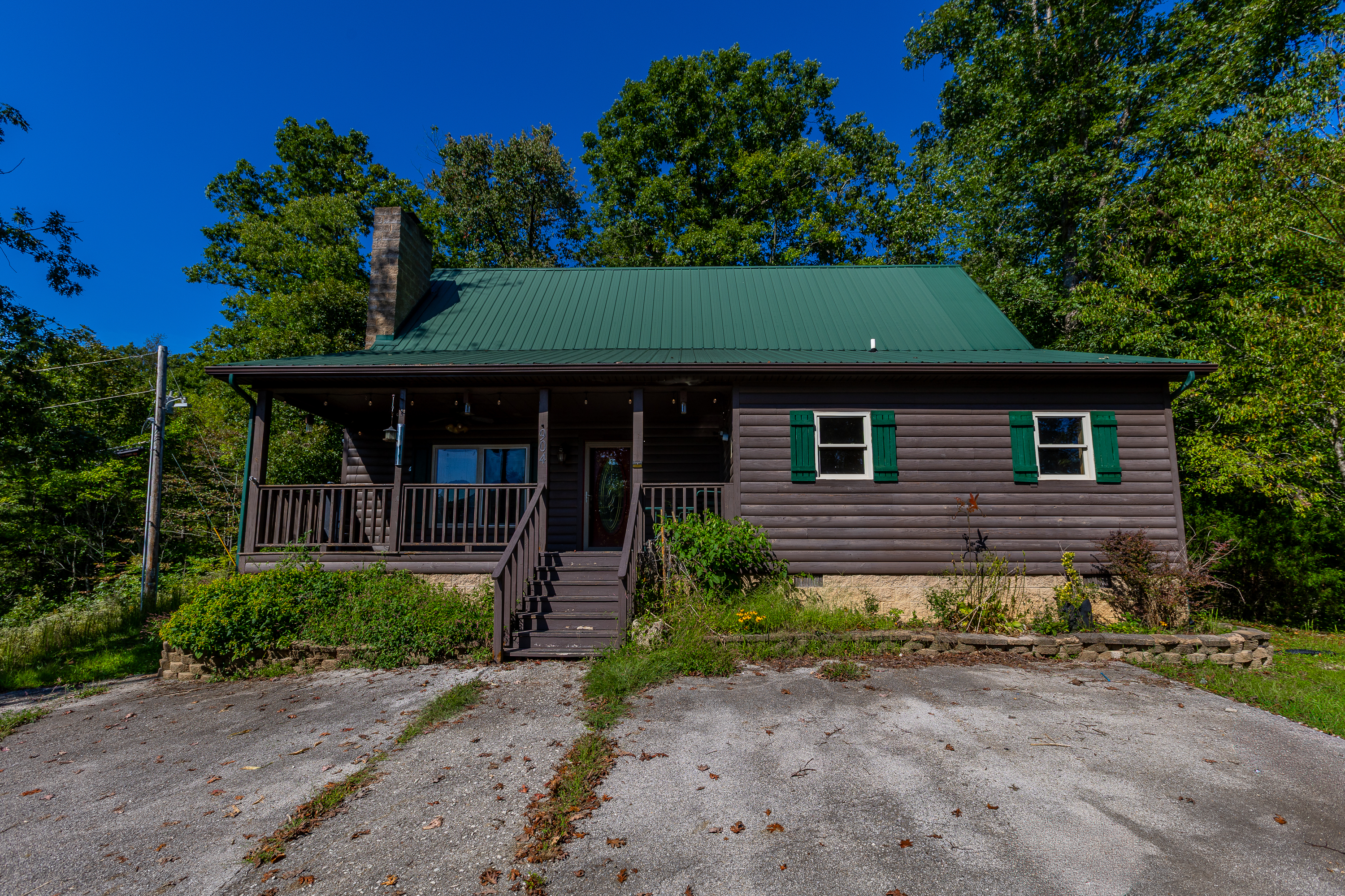 Front view of log home with green shutters and covered porch