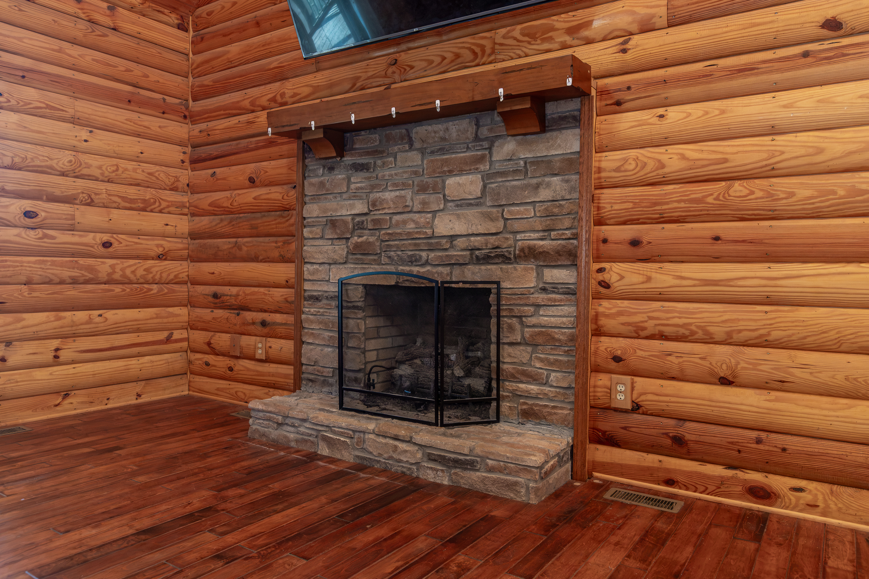 Stone fireplace with log walls and hardwood floors